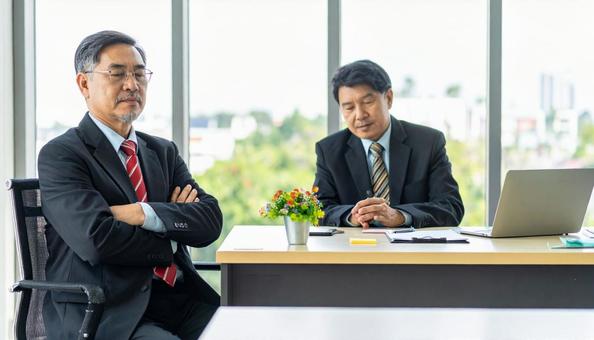 経営不振に腕を組んで悩む中小企業の社長の写真