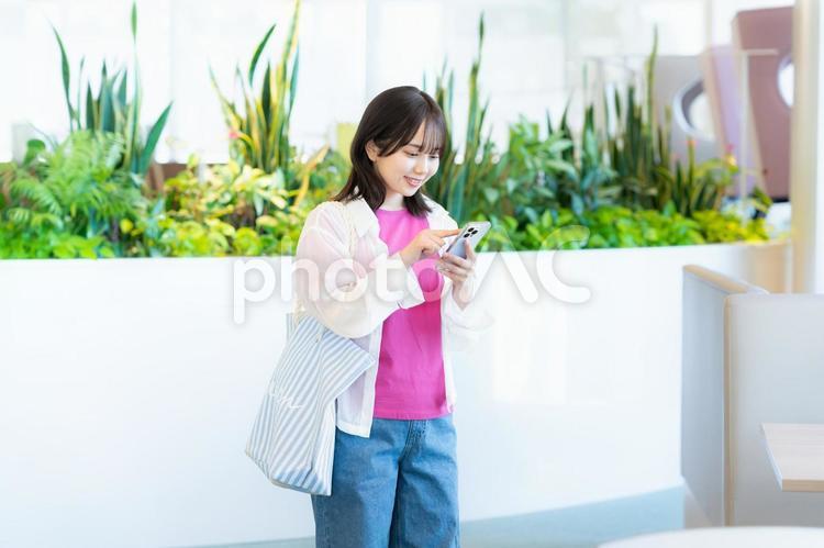 スマホを見る笑顔の女性 スマホ,若い女性,笑顔の写真素材