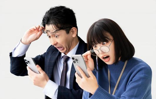 スマホを見て驚く男女2人のビジネスマン スマホを見て驚く男女2人のビジネスマン 男女,男性,女性の写真素材