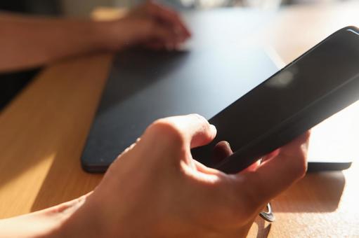 PCの前でスマホ入力する男性の手 スマートフォン,スマホ,携帯電話の写真素材