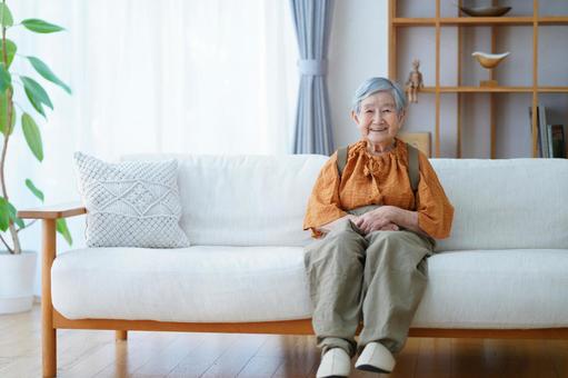 ソファに座り微笑む高齢女性 女性,笑顔,座るの写真素材