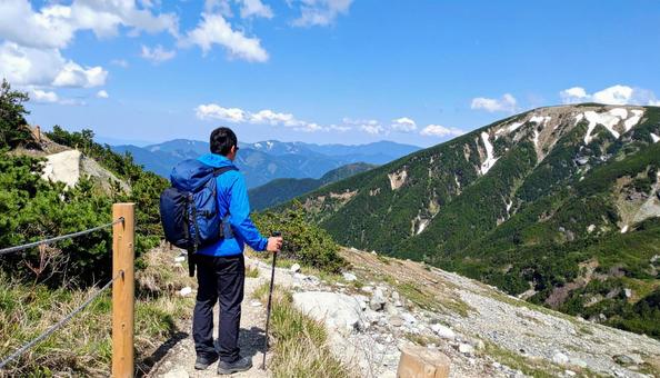 晴れた山に登山をする男性の後ろ姿 晴れた山に登山をする男性の後ろ姿の写真