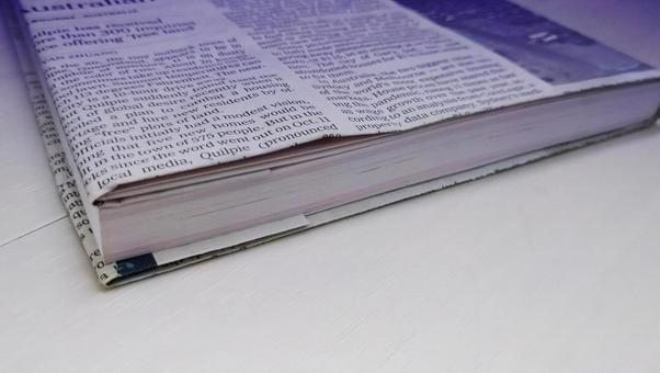 英字新聞のブックカバーをつけた書籍 英字新聞のブックカバーをつけた書籍 英字新聞,本,古本の写真素材