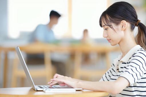 真顔でパソコンをす女性の横顔 女性,ノートパソコン,操作の写真素材