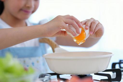 フライパンに卵を割り入れる女の子の手元 フライパン,卵,生卵の写真素材