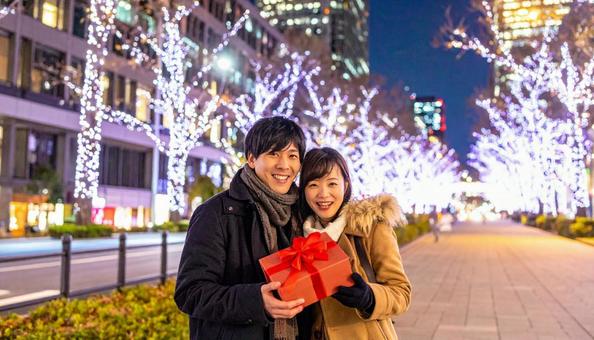 ギフトを手にする男女とイルミネーション ギフトを手にする男女とイルミネーションの写真