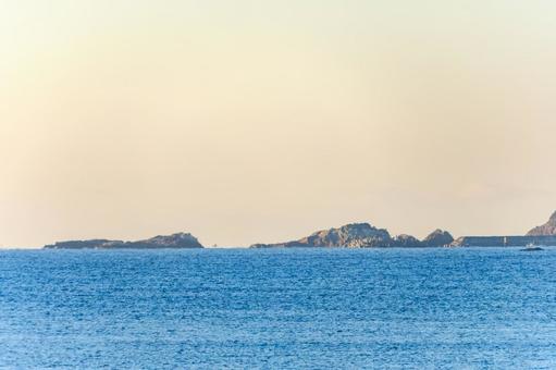 朝焼けに浮かぶ沖の岩礁と穏やかな海 朝焼けに浮かぶ沖の岩礁と穏やかな海の写真
