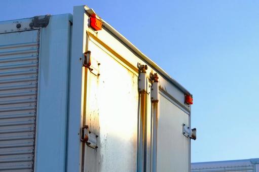 西日を浴びるトラックのリアの写真