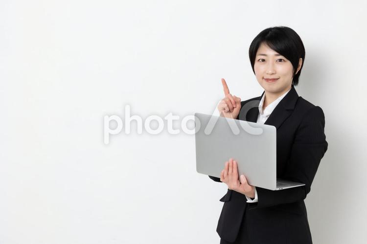 パソコンを持って指差しをしているビジネスウーマン（コピースペース） 女,女子,ビジネスウーマンの写真素材