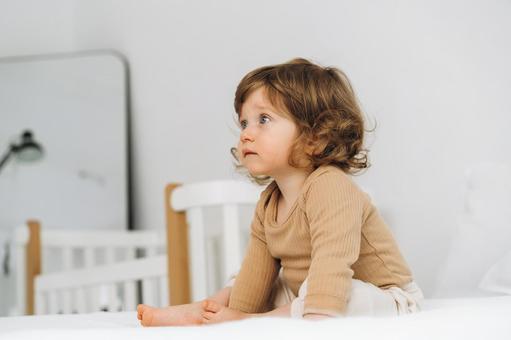 お座りするくせ毛の子供の横顔 お座りするくせ毛の子供の横顔 赤ちゃん,かわいい,お座りの写真素材