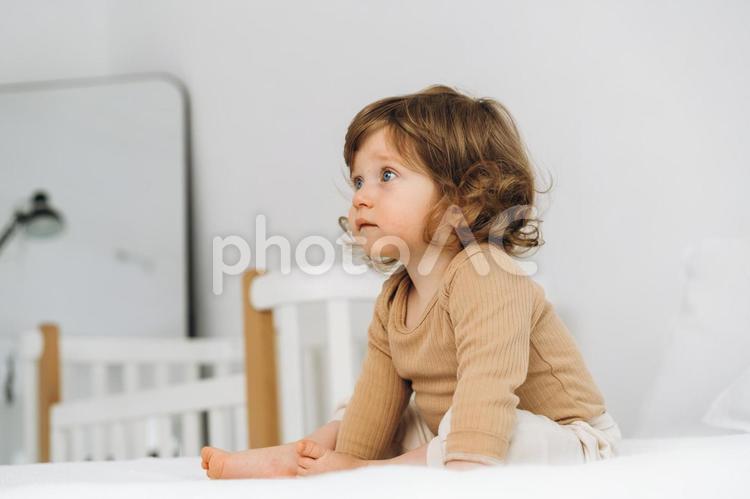 お座りするくせ毛の子供の横顔 赤ちゃん,かわいい,お座りの写真素材
