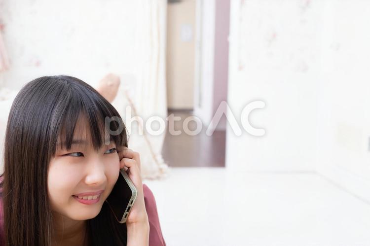 寝ながらスマートフォンで電話をしている女性 女性,人物,日本人の写真素材