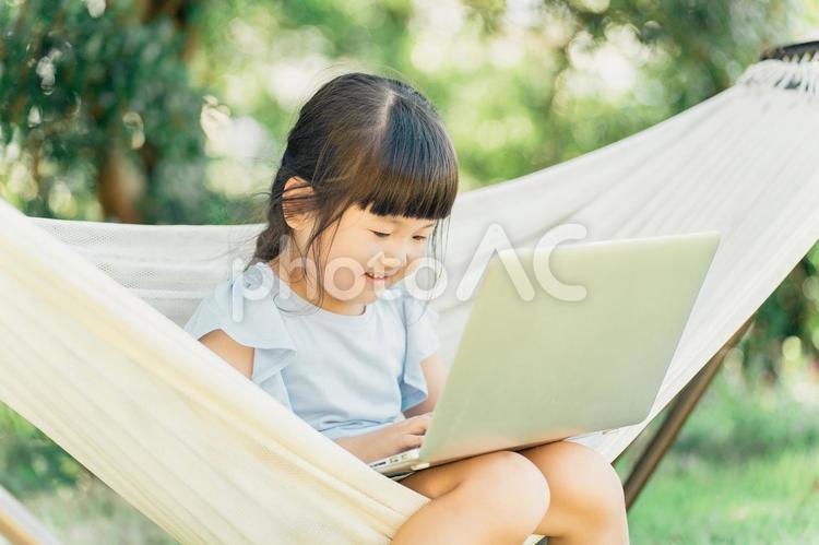 ハンモックに乗り動画を見る子供 子供,パソコン,ノートパソコンの写真素材