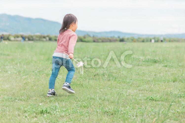 広い公園でおもちゃを持って走り回る子供 子供,女の子,子どもの写真素材