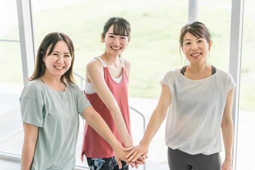 スポーツジムで仲間と円陣を組む女性達 スポーツジムで仲間と円陣を組む女性達 友達,仲間,団結の写真素材