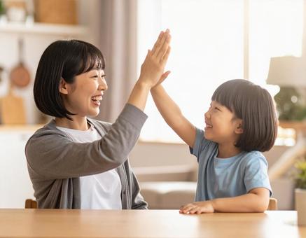 家庭でハイタッチするお母さんと子供 家庭でハイタッチするお母さんと子供の写真