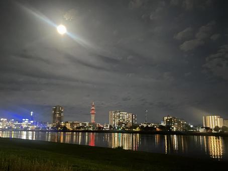 雲間から照らす月とリバーサイドの夜景 夜景,都市,リバーサイドの写真素材