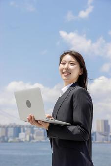 ノートパソコンで調べるビジネスウーマン ノートパソコンで調べるビジネスウーマン 女性,リクルートスーツ,見上げるの写真素材