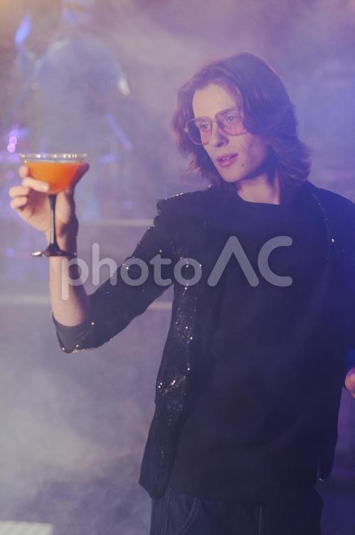 オレンジ色のカクテルを見つめる男性 男性,カクテル,飲み物の写真素材