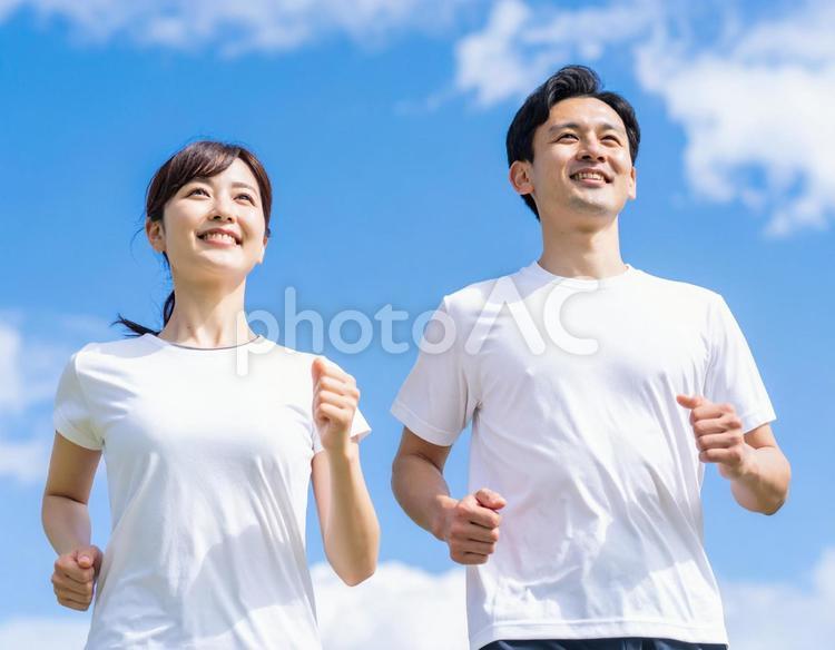 青空の下、ジョギングする男女 走る,青空,ジョギングの写真素材