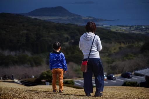 ＜素材＞山の上から街並みと海を眺める親子 女性,子供,男性の写真素材