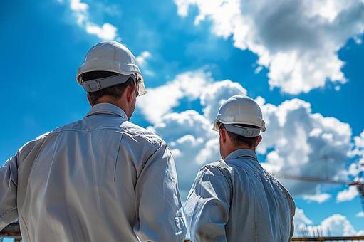 現場で働く建設作業員の後ろ姿と青空の写真