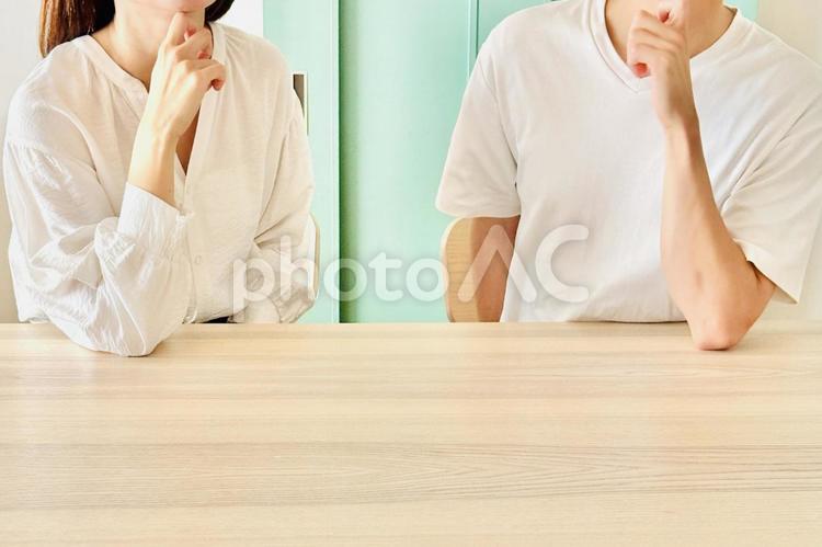 顎に手を当てて一緒に考える若い夫婦 悩む,相談,疑問の写真素材