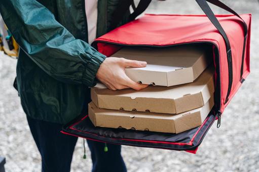 保温ピザバッグからピザを出す男性 配達,フードデリバリー,デリバリーの写真素材