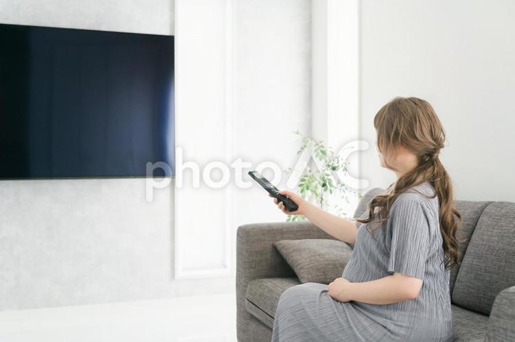 テレビのリモコンを持つ妊婦の女性（産休） 妊婦,リモコン,妊娠の写真素材