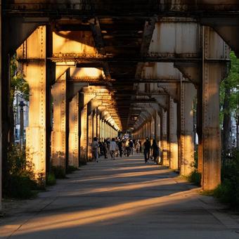 橋の下を歩く人々と夕暮れの都市風景の写真