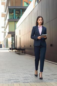 街なかでタブレットを持って歩くビジネスウーマン ビジネスウーマン,ビジネス,女性の写真素材