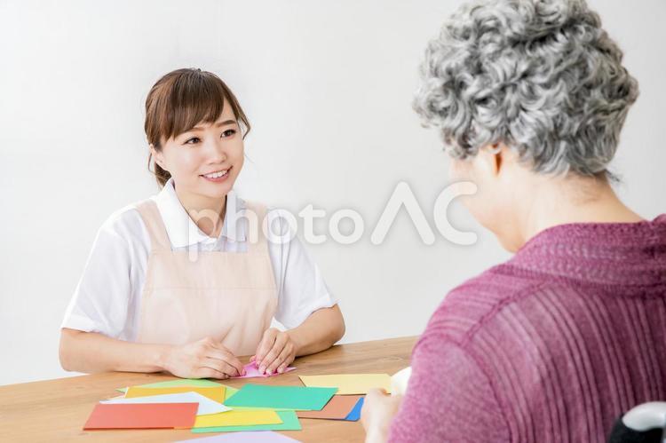 折り紙でレクリエーションする介護士と高齢者の女性 老人ホーム,折り鶴,レクリエーションの写真素材