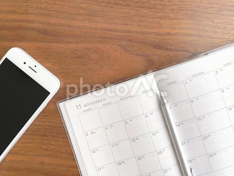 机上のスマホと11月のスケジュール帳 カレンダー,手帳,予定の写真素材