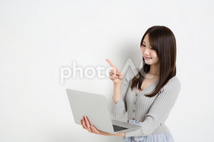 パソコンを持って指差ししている若い女性（コピースペース） 女性,女の子,女の写真素材