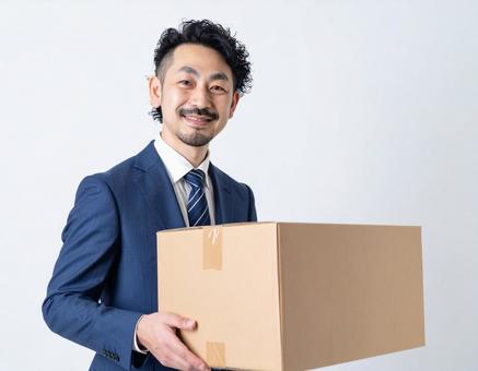 段ボール箱を運ぶビジネスマンの写真