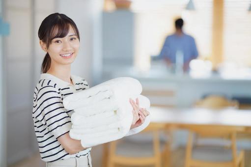 畳んだタオルを持ち振り向く女性の写真