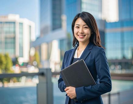 オフィスでPCを持って微笑む女性社員 オフィスでPCを持って微笑む女性社員の写真