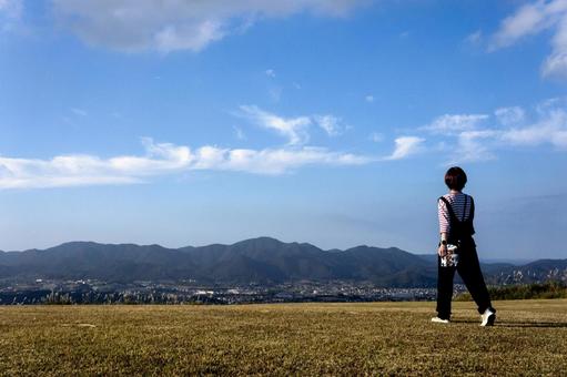 ＜素材＞山頂を散歩する女性の後ろ姿 女性,空,ウォーキングの写真素材
