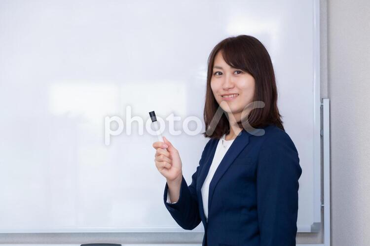ホワイトボードの前でマジックを持つスーツの女性 女性,スーツ,ホワイトボードの写真素材