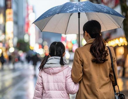 雨の中一つの傘に入る親子 雨の中一つの傘に入る親子の写真