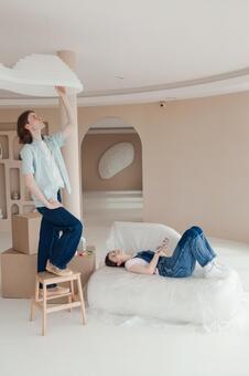 部屋の模様替えをする男性と色見本を持ち寝そべる女性 男女,寝転ぶ,休憩の写真素材