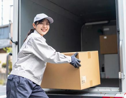 トラックから荷物を出す宅配女性ドライバー トラックから荷物を出す宅配女性ドライバーの写真