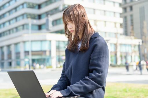ベンチに座ってパソコンを操作する女子高生 高校生,女子高生,女性の写真素材