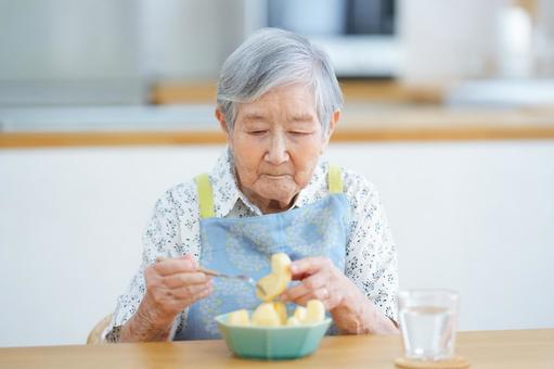 フォークに刺したリンゴを押さえる高齢女性 女性,リンゴ,フルーツの写真素材