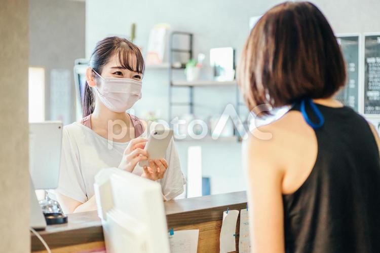 受付でスマホを出す女性（マスク） スマホ,受付,ポイントの写真素材