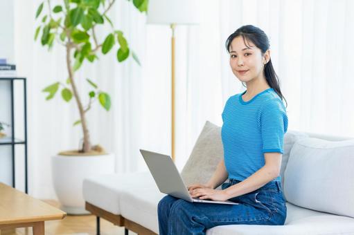 部屋でパソコンを操作する女性 部屋でパソコンを操作する女性 女性,ライフスタイル,微笑みの写真素材