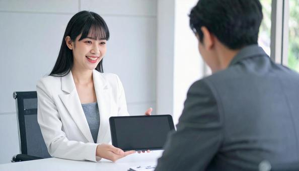 タブレットを使って説明する女性営業マン タブレットを使って説明する女性営業マンの写真