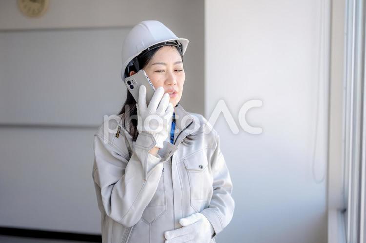 困り顔で電話する作業員女性 女性,作業員,建設の写真素材