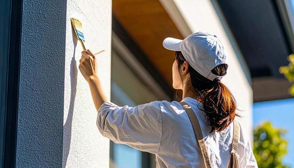 DIYで外壁塗装する女性の写真