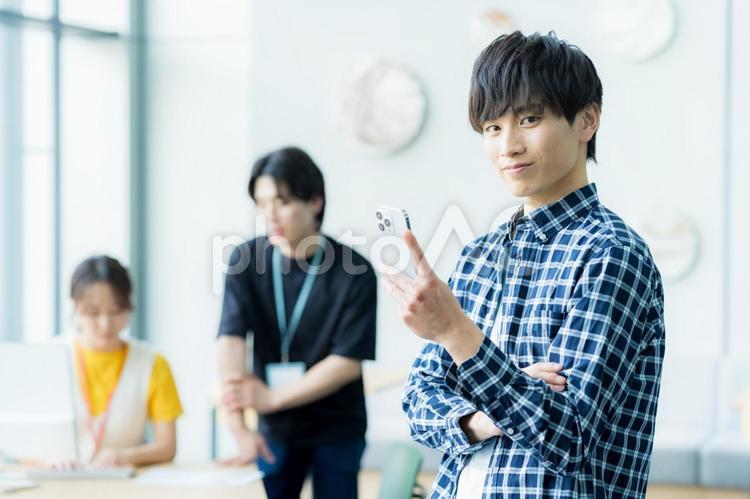 オフィスでスマホを操作するビジネスマン ビジネスマン,スマホ,笑顔の写真素材
